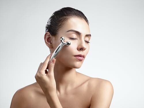 Woman using a facial massager on her cheek.